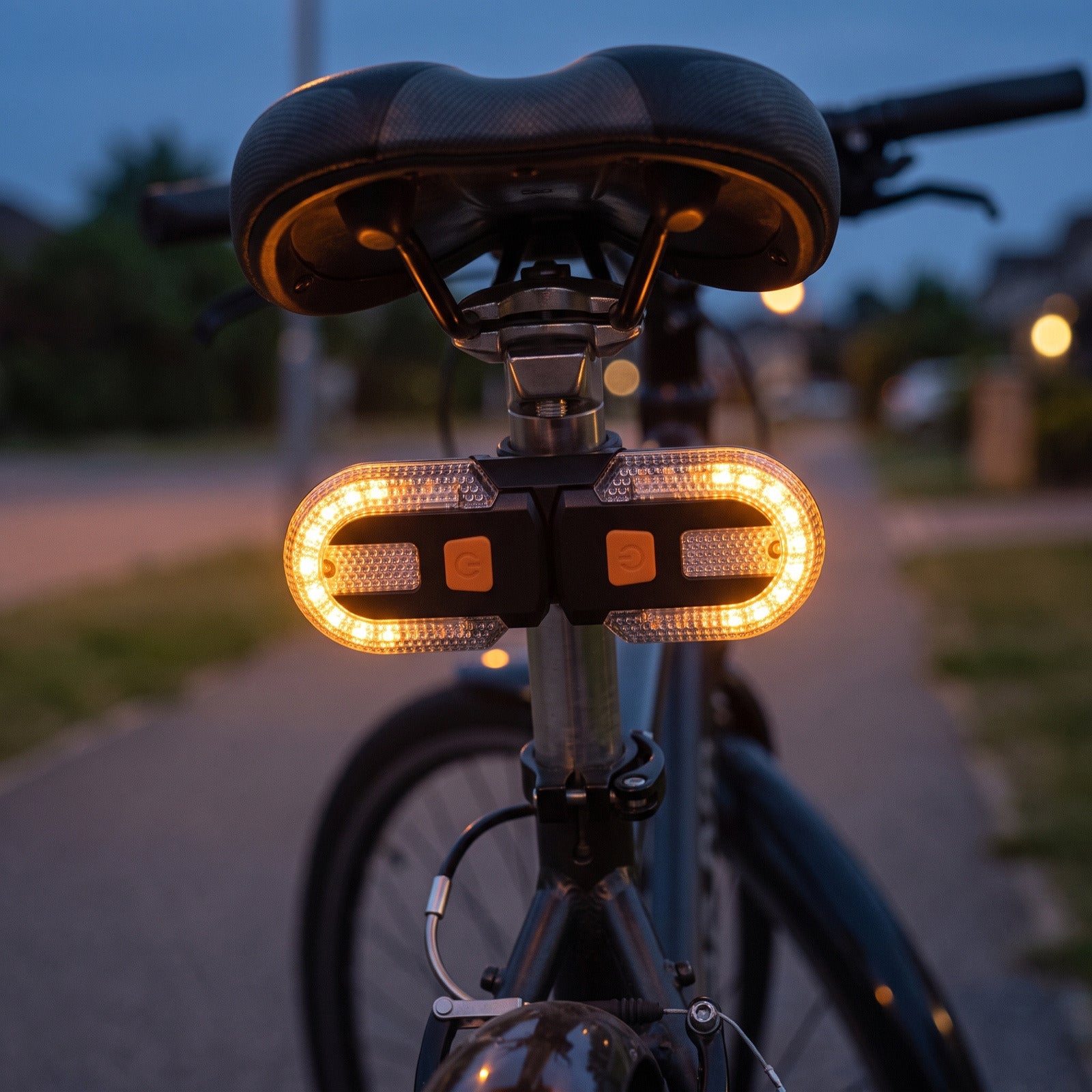 Rear turn signal lamp glowing under a bicycle saddle